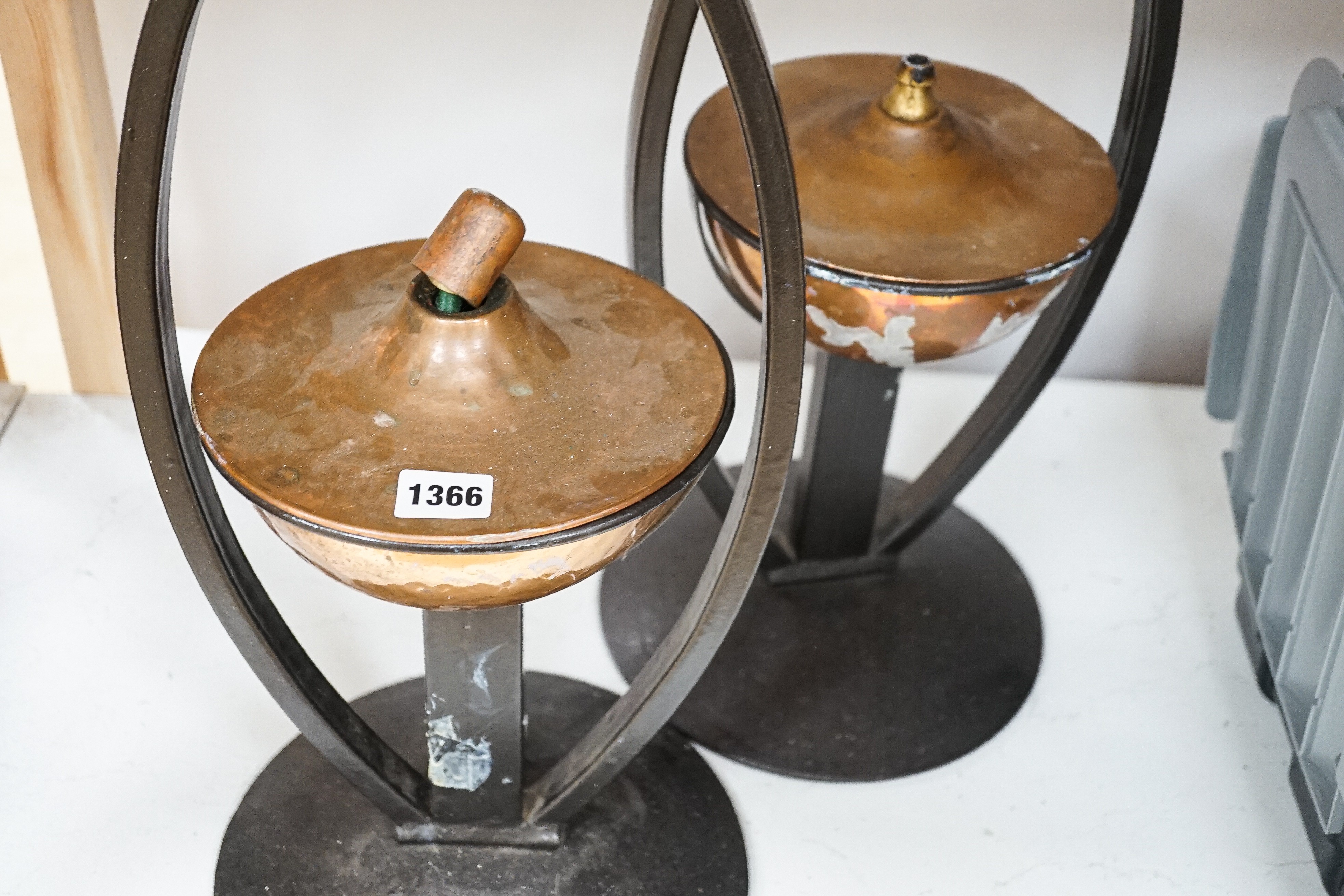 A pair of decorative copper lamps in arched mounts, 61 cms high.